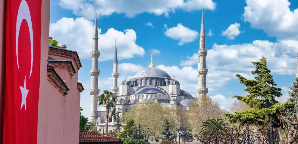 The blue mosque in Istanbul with a Turkish flag in the background, perfect for exploring Istanbul on your itinerary.