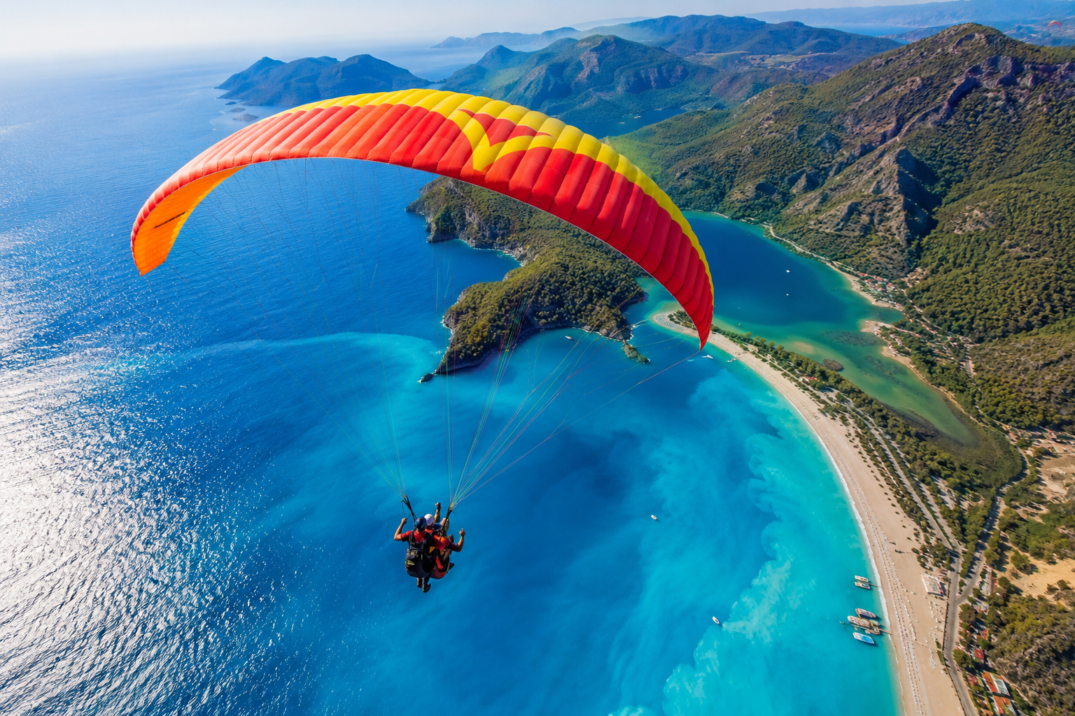 () action photograph of a tandem paraglider in flight high above &Ouml;l&uuml;deniz Blue Lagoon, shot from slightly above and behind